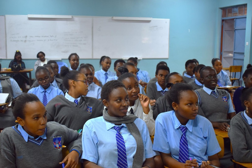 A classroom of African high school students in blue uniforms listening and learning
